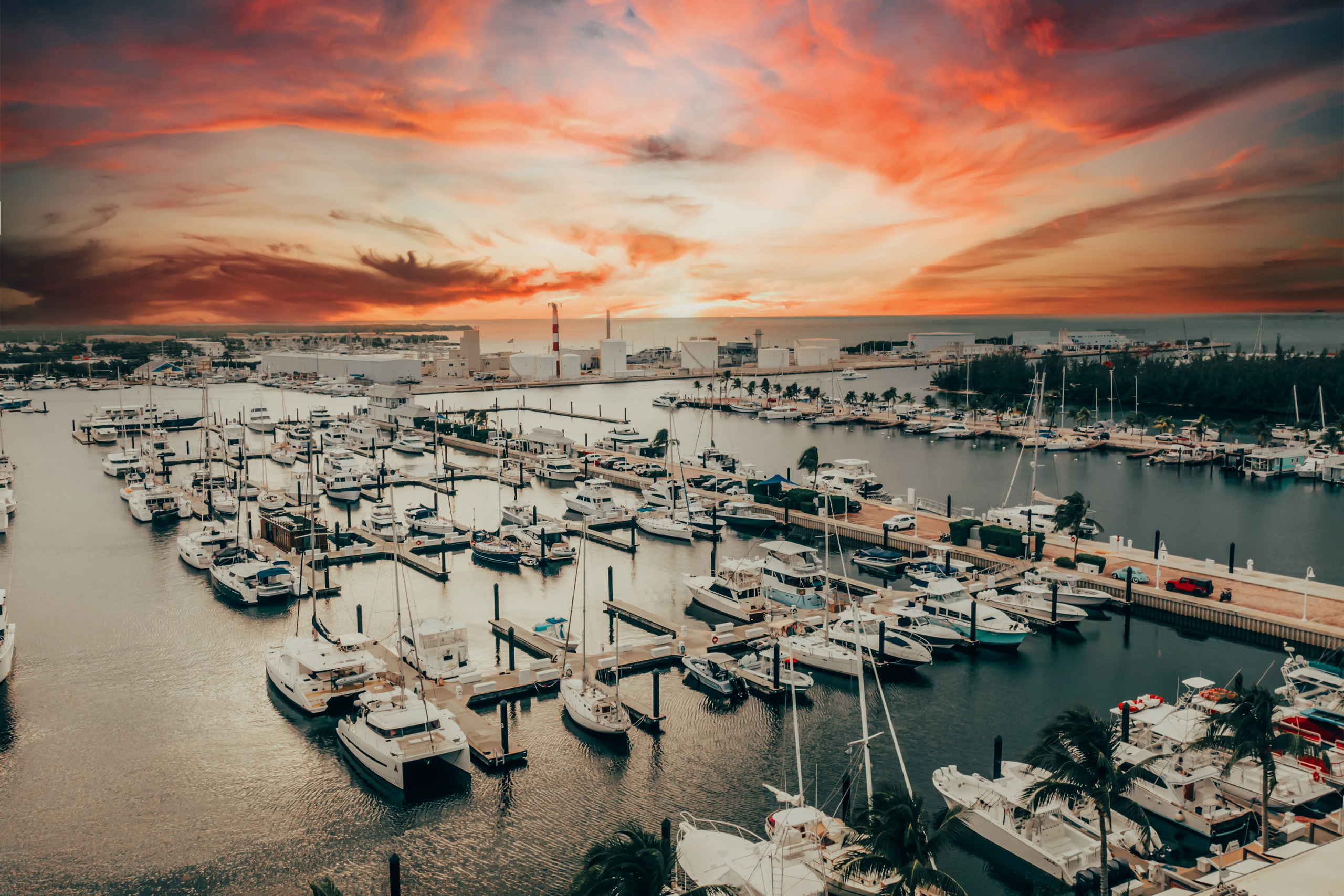 Marina filled with yachts and sailboats under vibrant sunset sky.