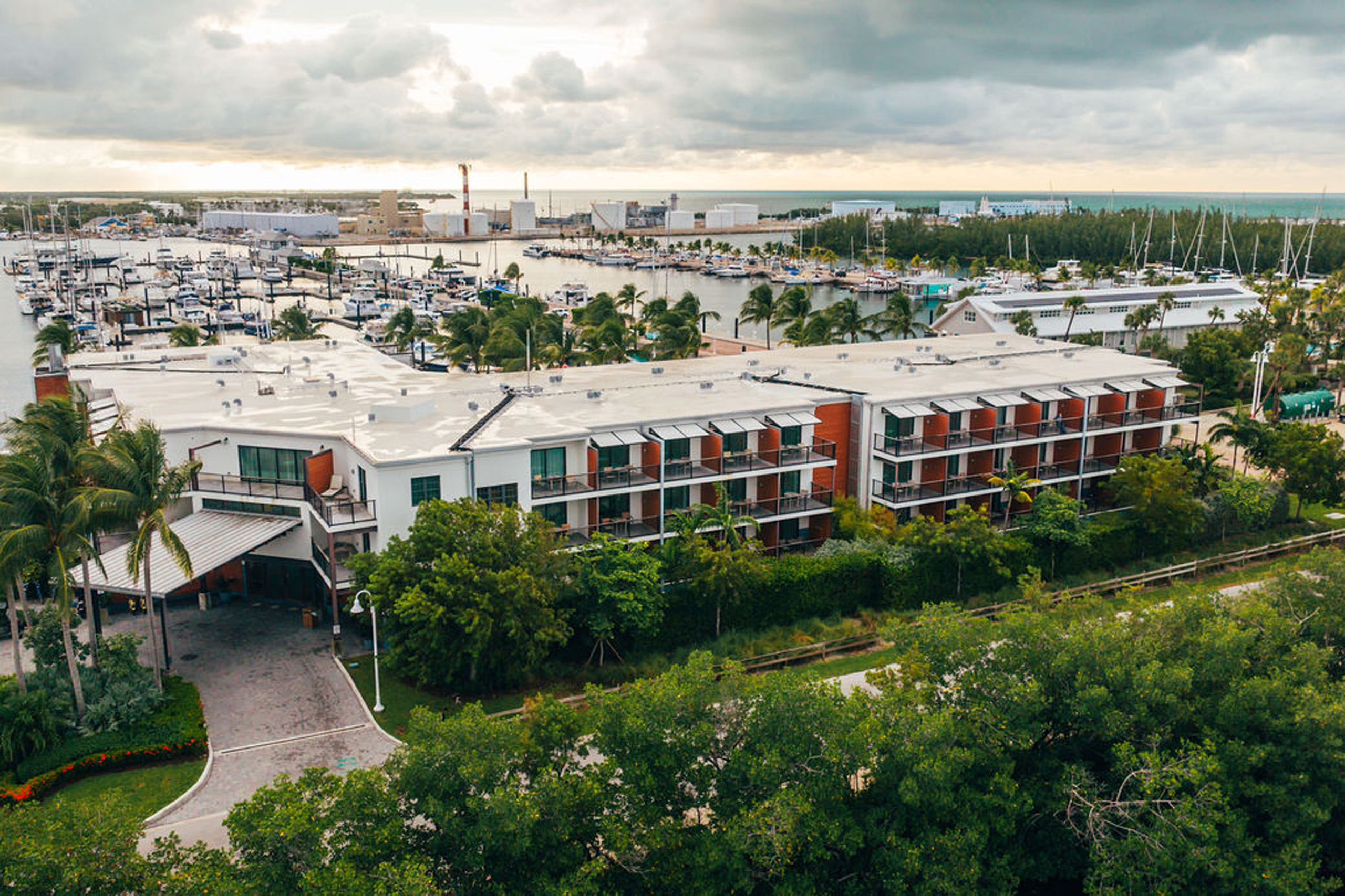 Aerial of hotel exterior overlooking marina under clouds.