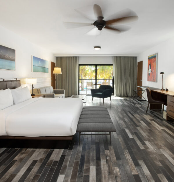 A plush king bed with leather headboard, queen sleeper sofa, modern lounge seating, and a padded bench at the foot of the bed.