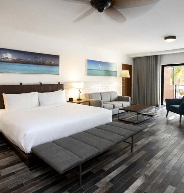 Suite angle with king bed, sofa, lounge chair, and balcony.