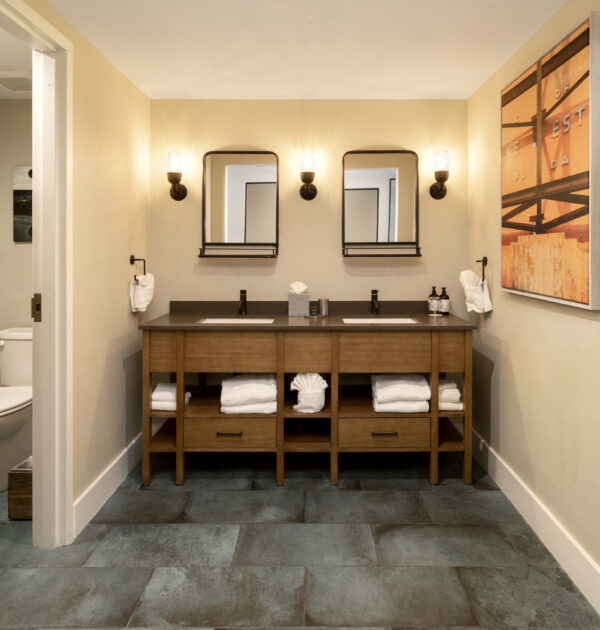 Double vanity with elegant lighting, glass-enclosed shower, and separate soaking tub.