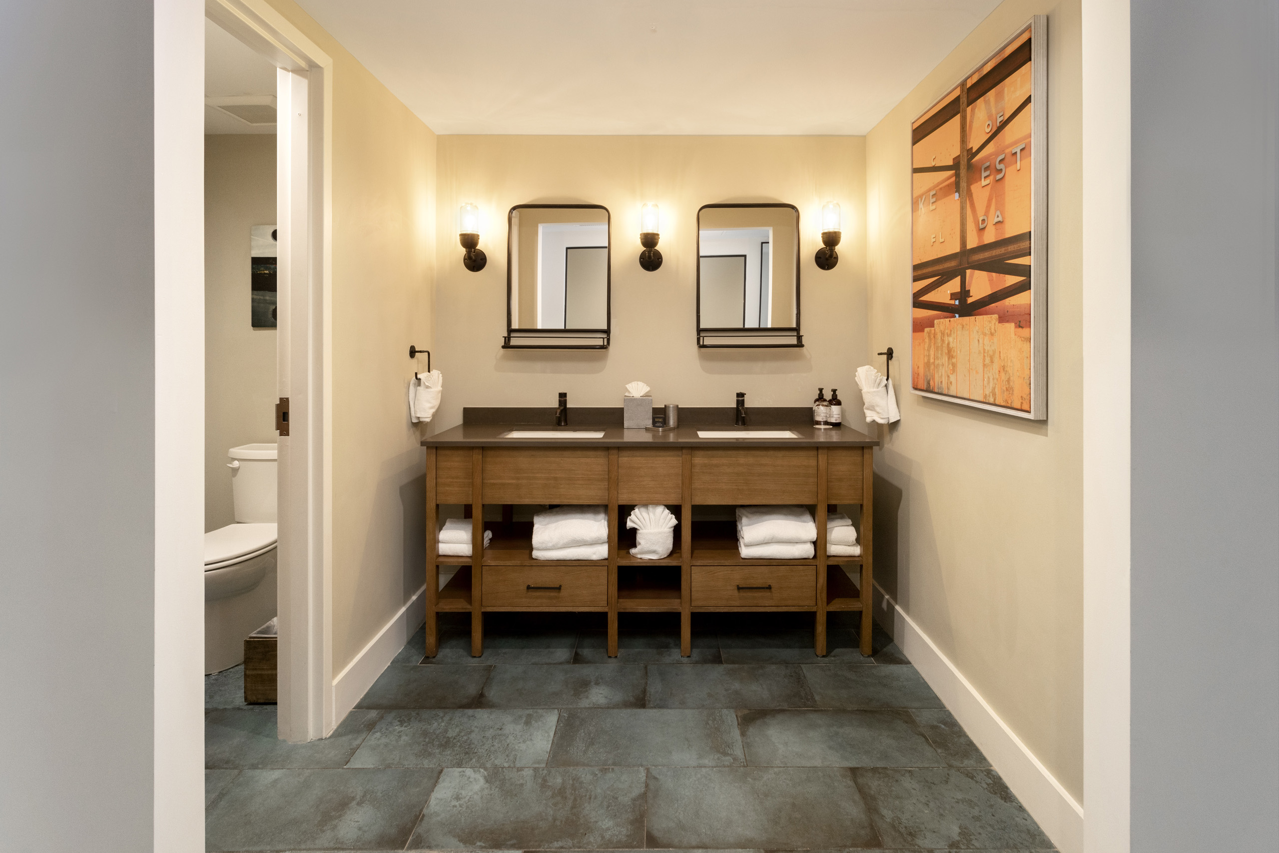 Double vanity with elegant lighting, glass-enclosed shower, and separate soaking tub.