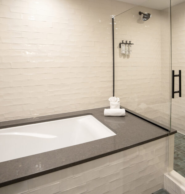 Bathroom with soaking tub beside glass shower and tiled walls.