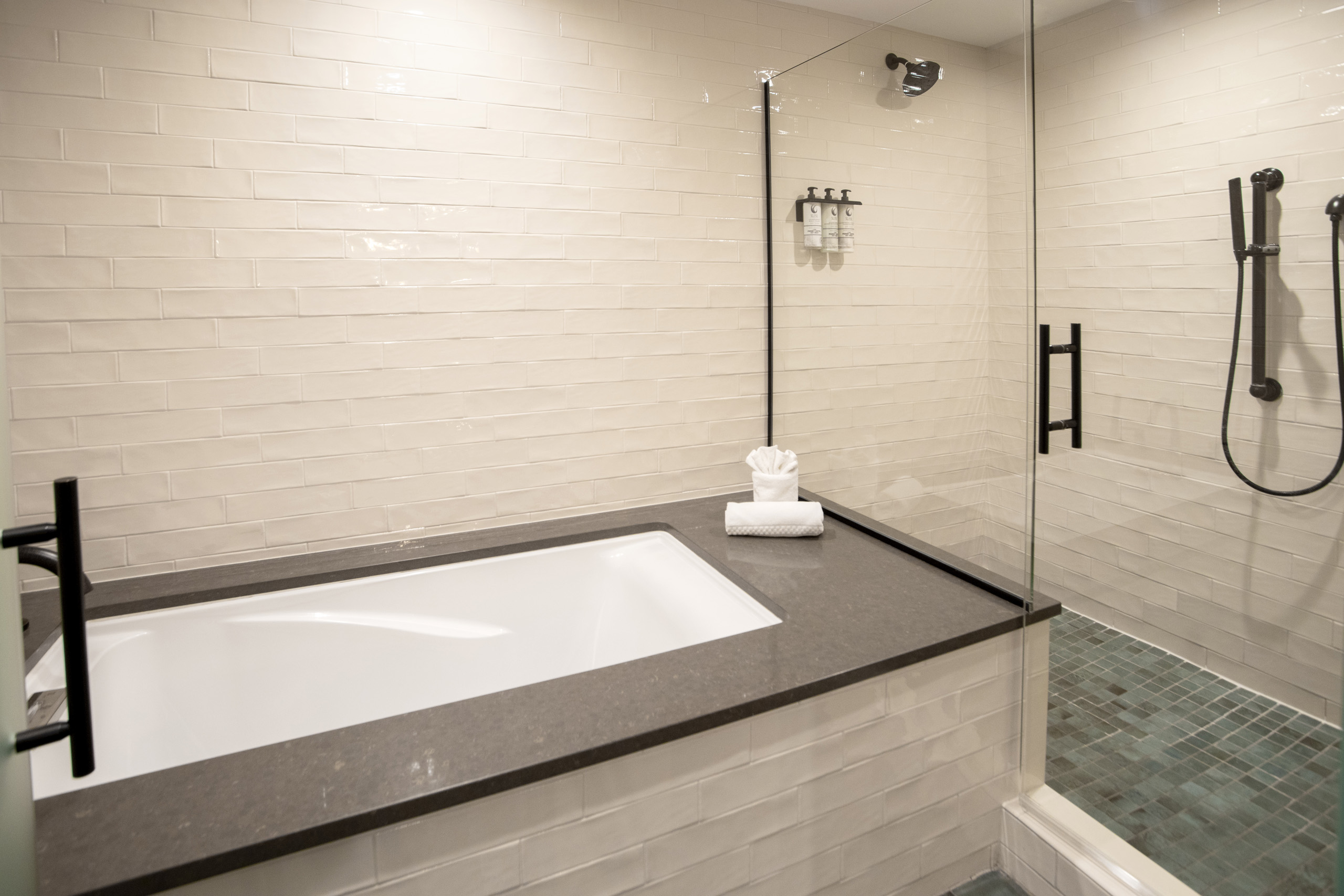 Bathroom with soaking tub beside glass shower and tiled walls.