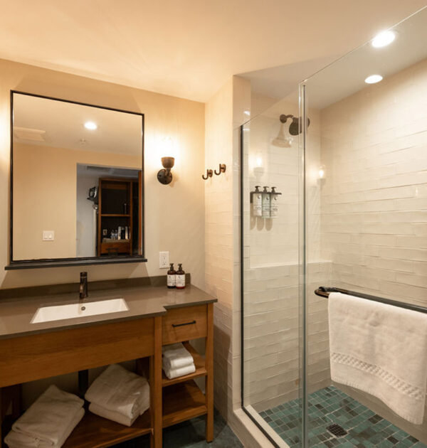 Bathroom with vanity, mirror, sconces, and glass shower enclosure.