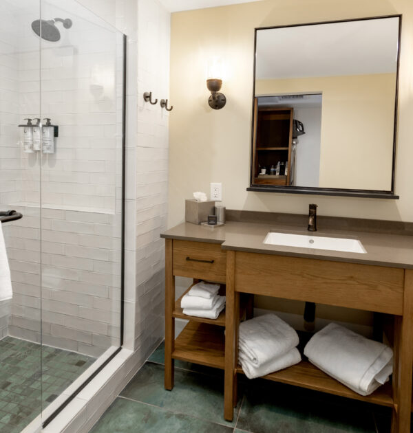 Bathroom vanity with towels and glass shower, warm lighting.