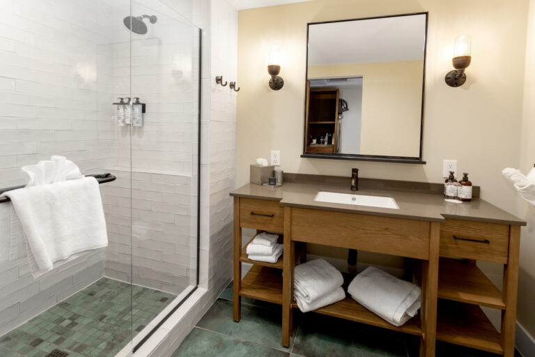 Bathroom with vanity, mirror, towels, and glass shower enclosure.
