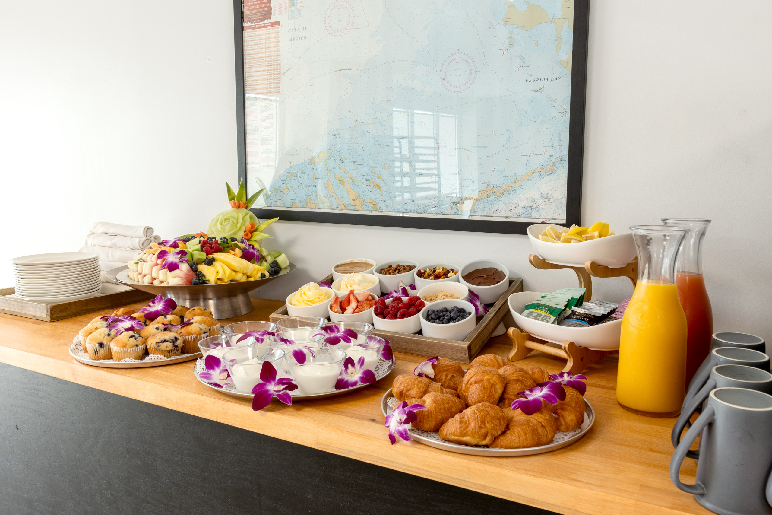 Colorful catering spread with pastries, fruit, and juices.