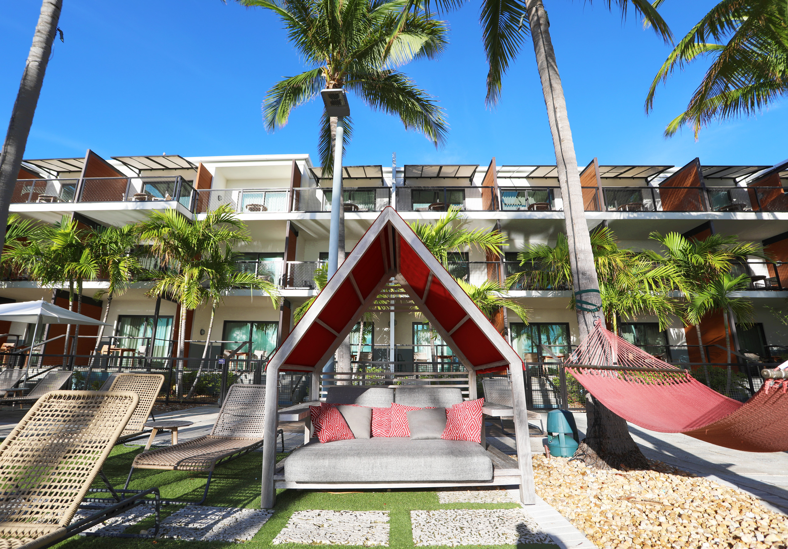 Poolside cabana with hammock and shaded lounge seating.