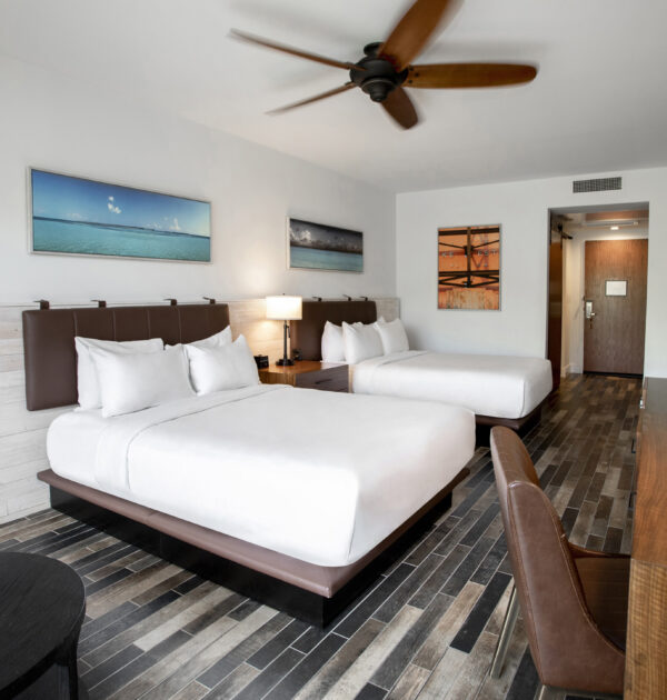 Spacious hotel room with two queen beds and desk.