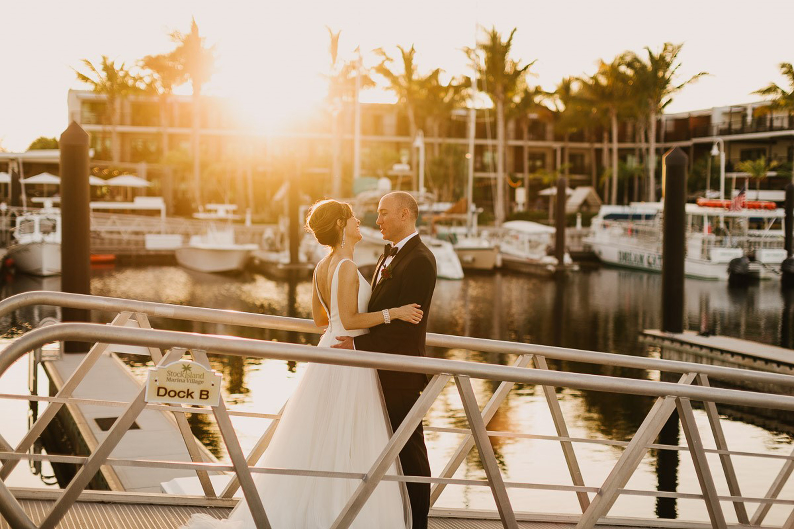 Couple embracing at sunset on marina dock.