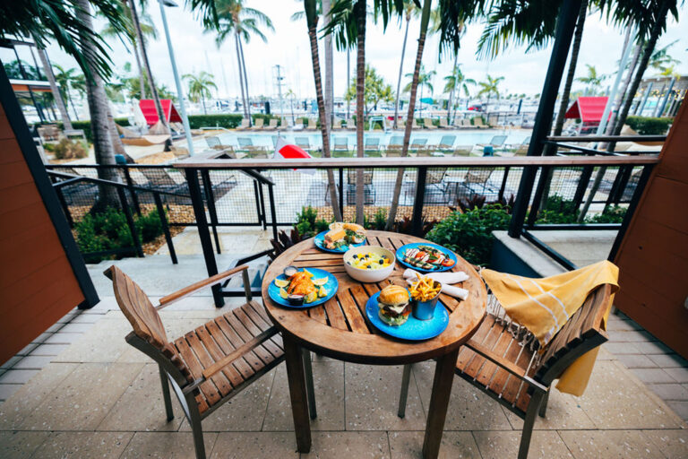 Patio table set with plates of food, overlooking poolside area.