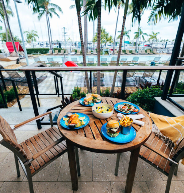 Patio dining setup with food and drinks on round table.