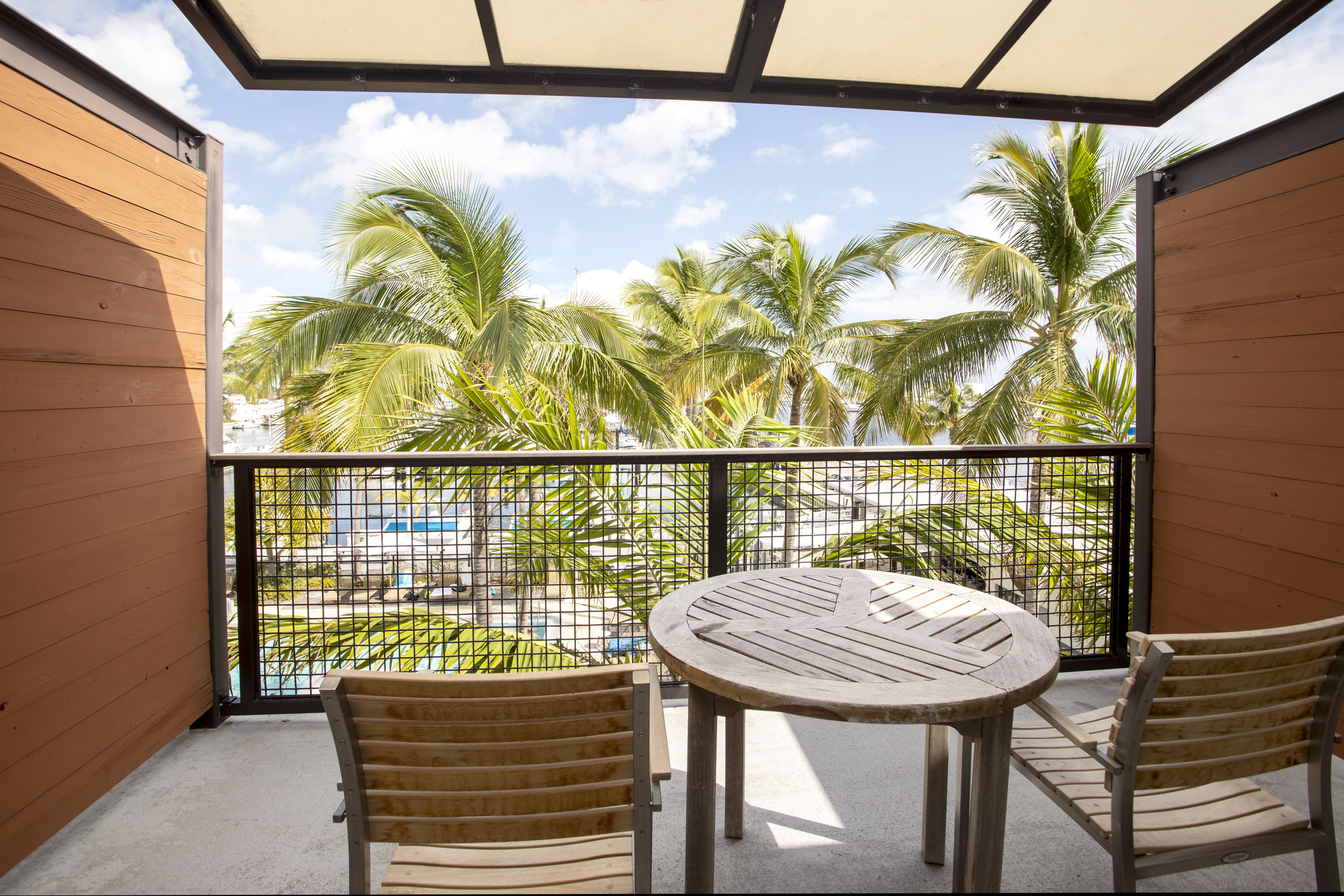 Balcony with wooden table, two chairs, and palm tree views.