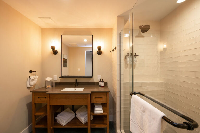 Modern bathroom vanity with mirror and glass shower enclosure.