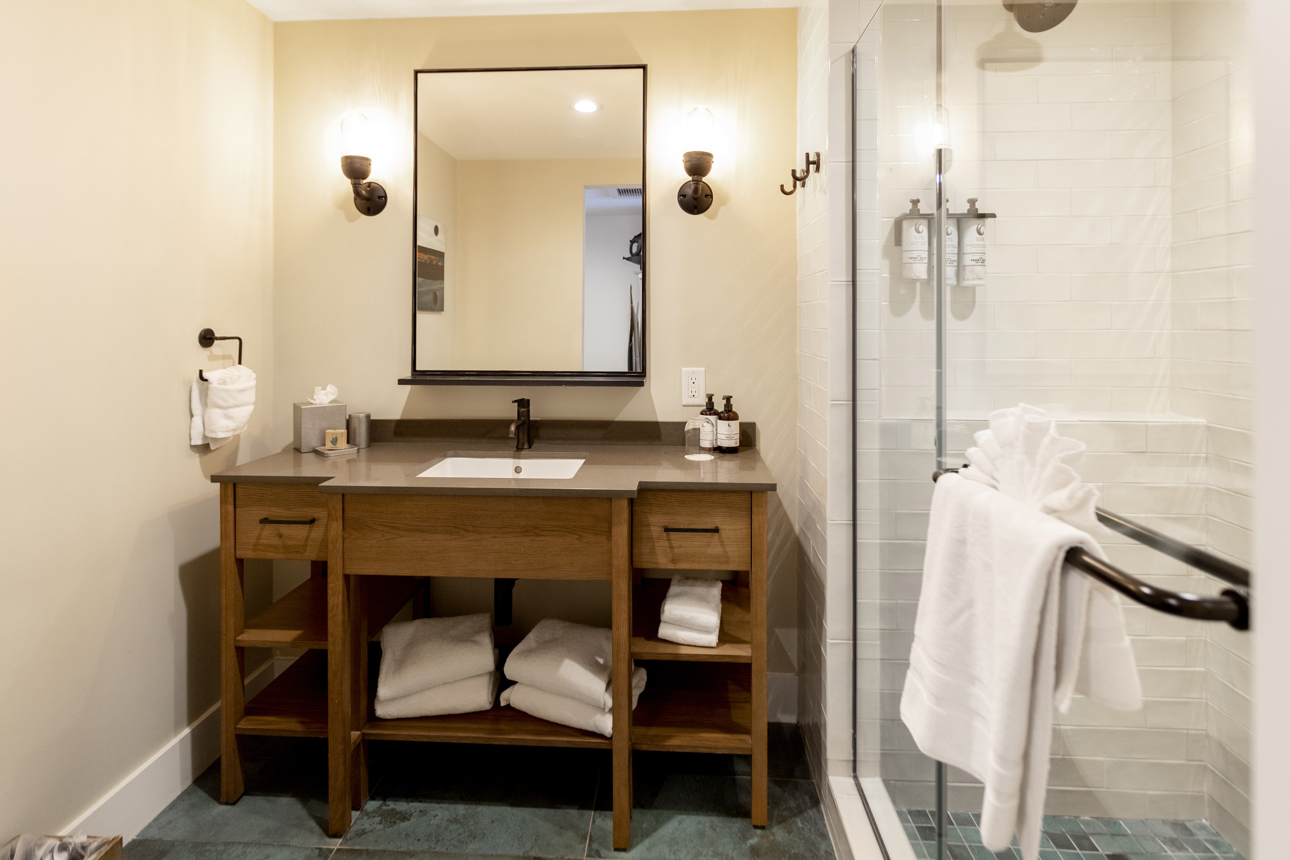 Modern hotel bathroom with vanity, mirror, and glass shower.