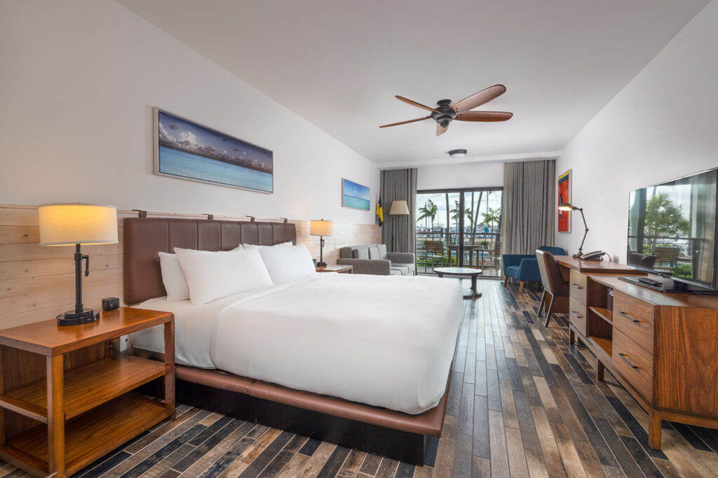 Modern guest room with king bed, sofa, and private balcony.