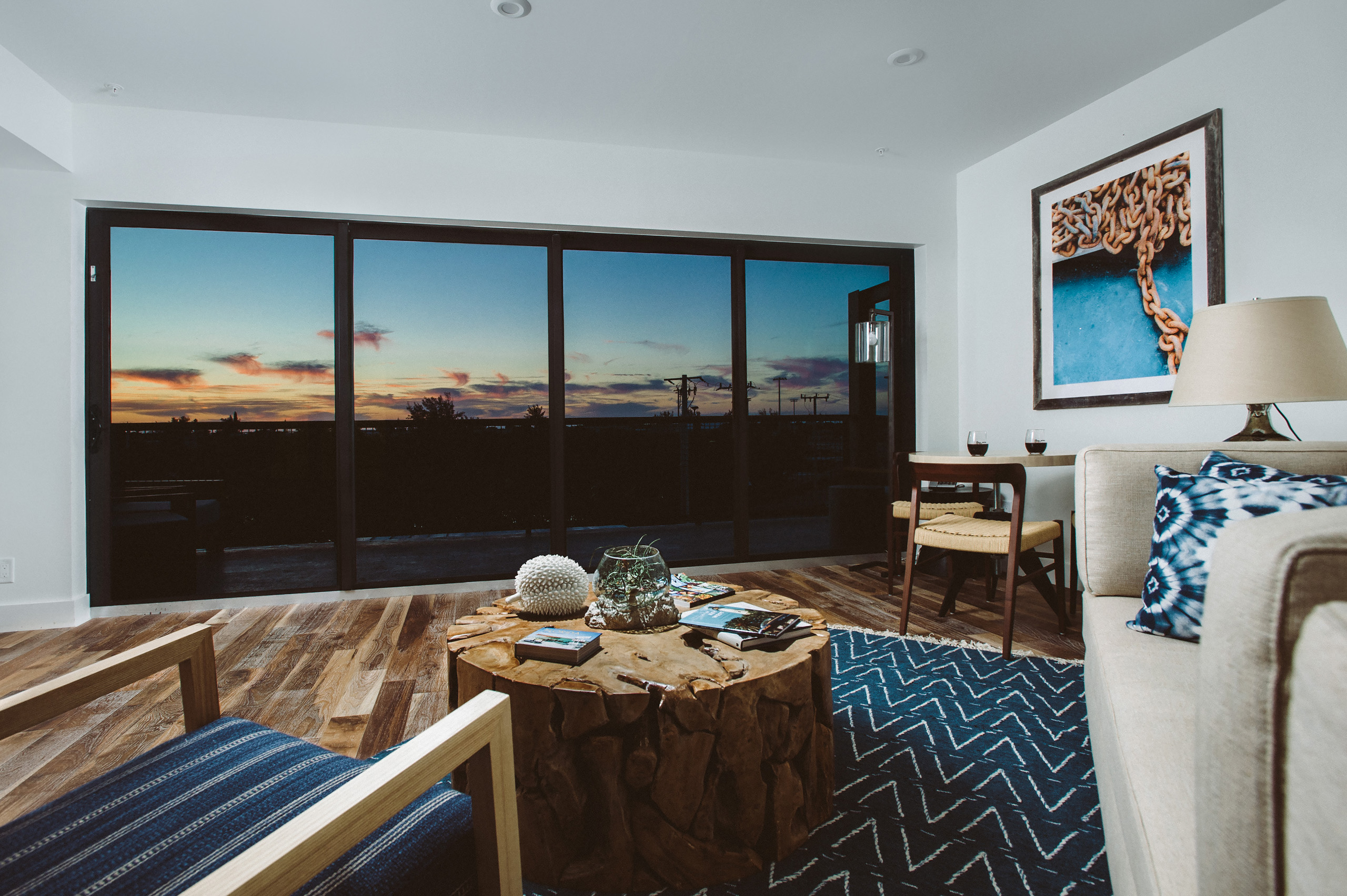 Cozy lounge with wood coffee table, floor-to-ceiling sunset views.