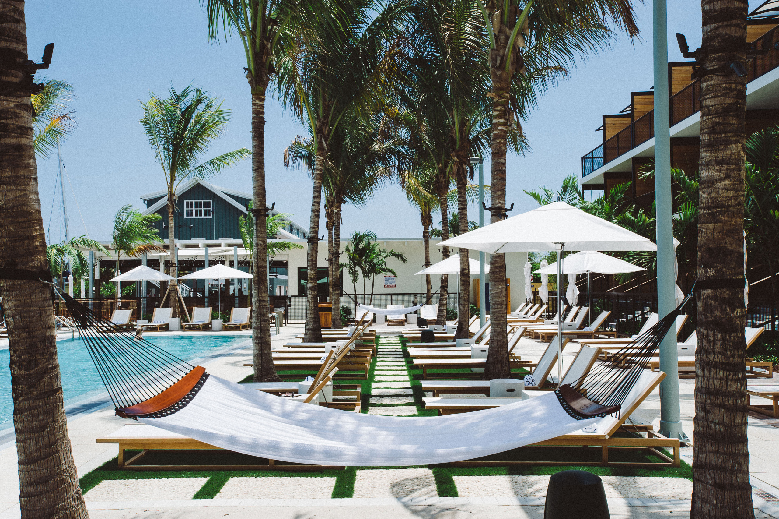 Poolside hammock with rows of lounge chairs under umbrellas.