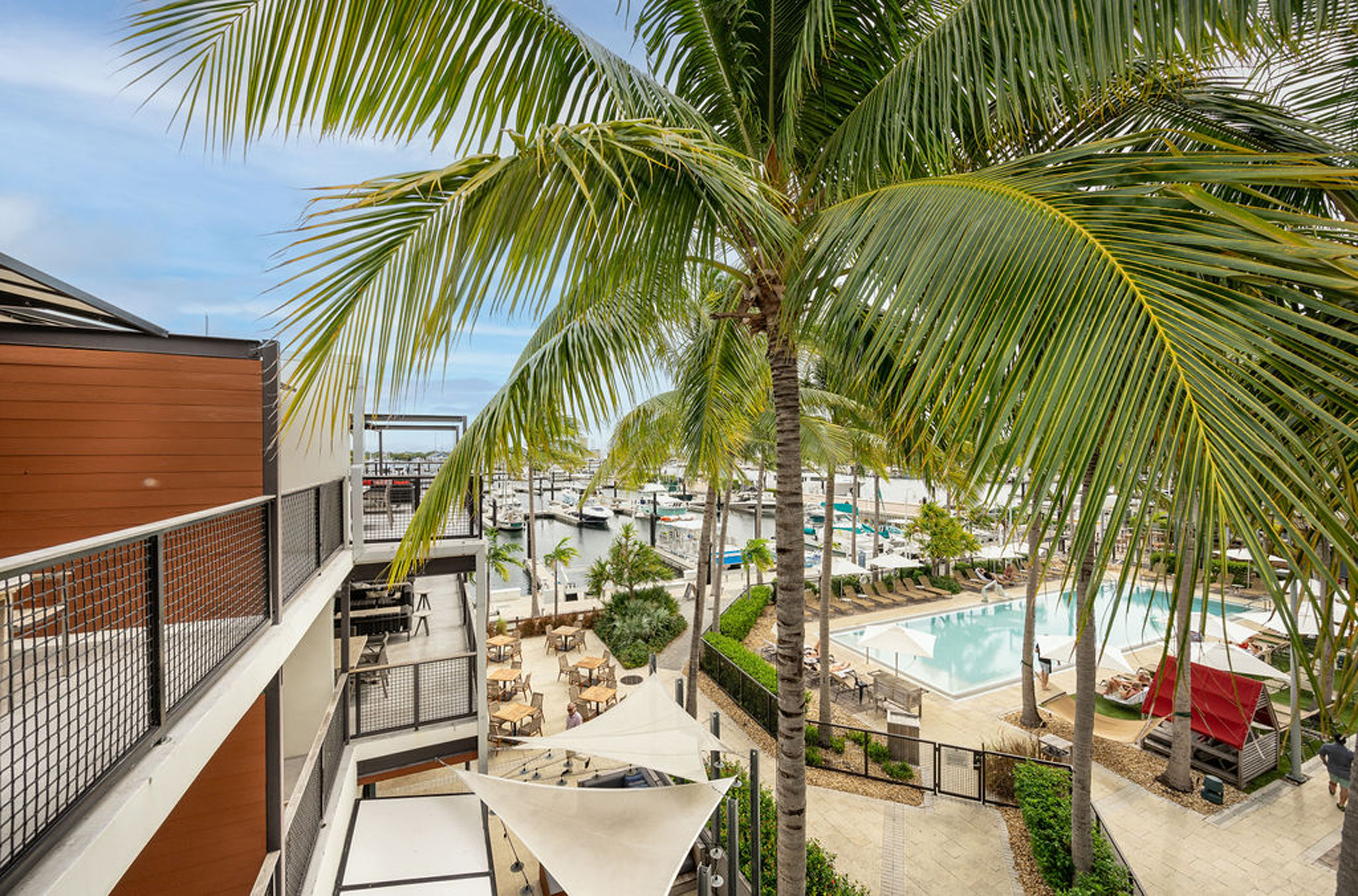 Elevated view of pool, cabanas, and marina with palm trees.