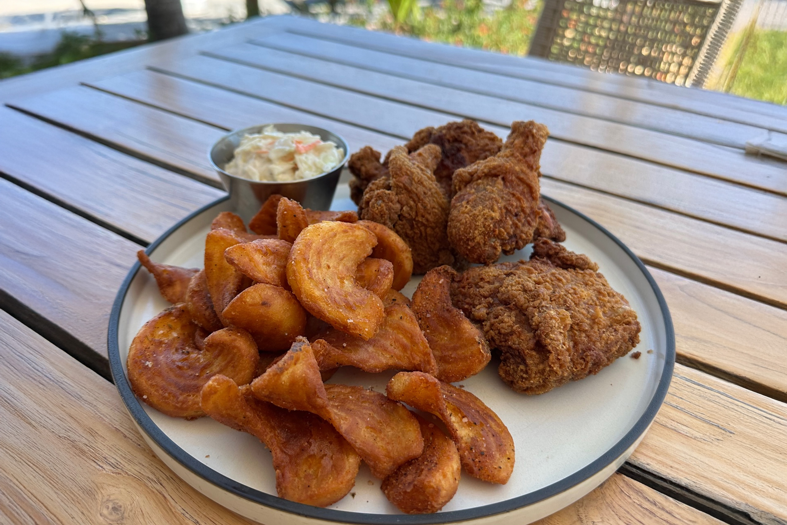 Fried chicken with curly fries and coleslaw, marina view.