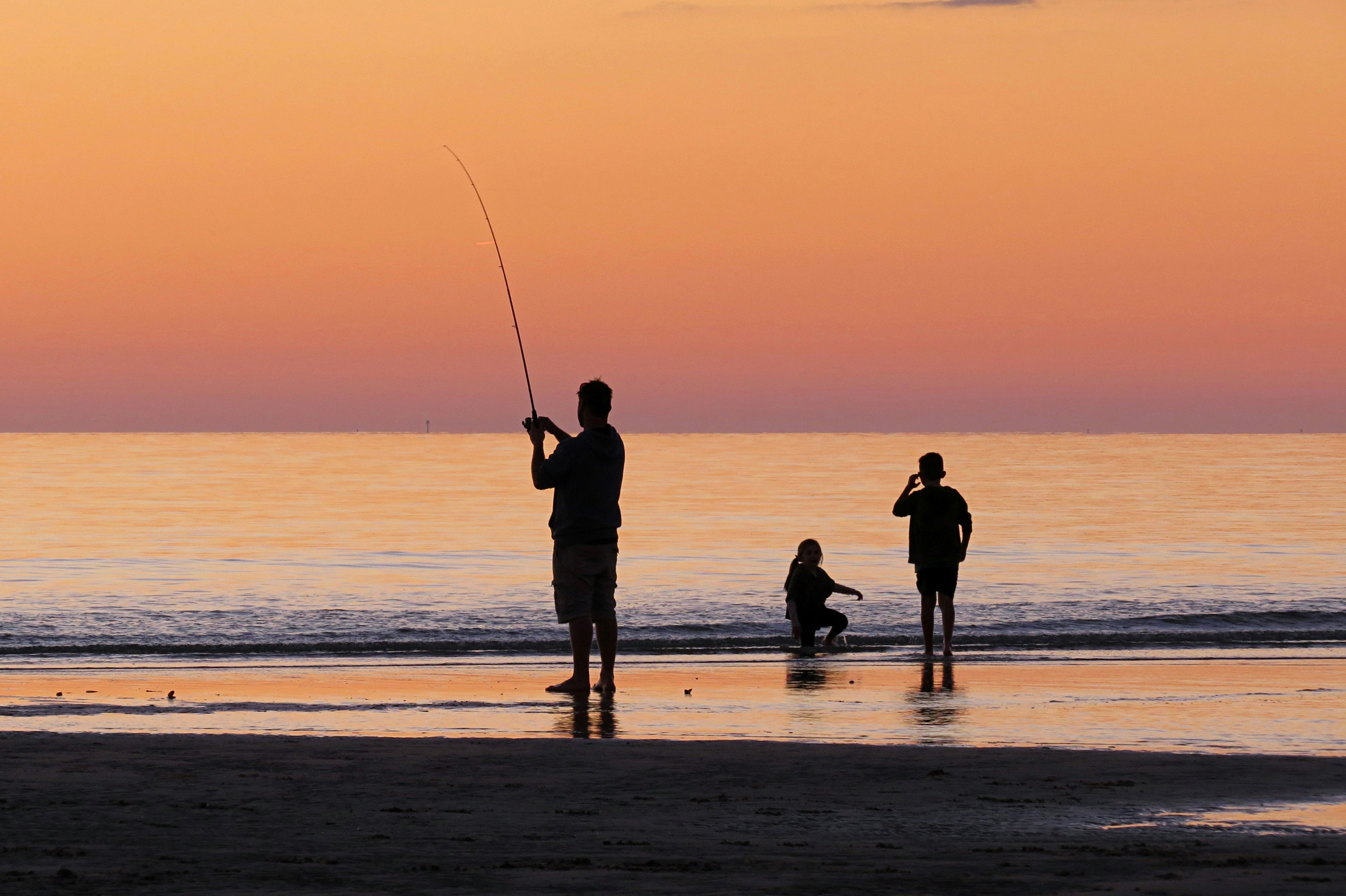 People fishing at sunset on the beach.