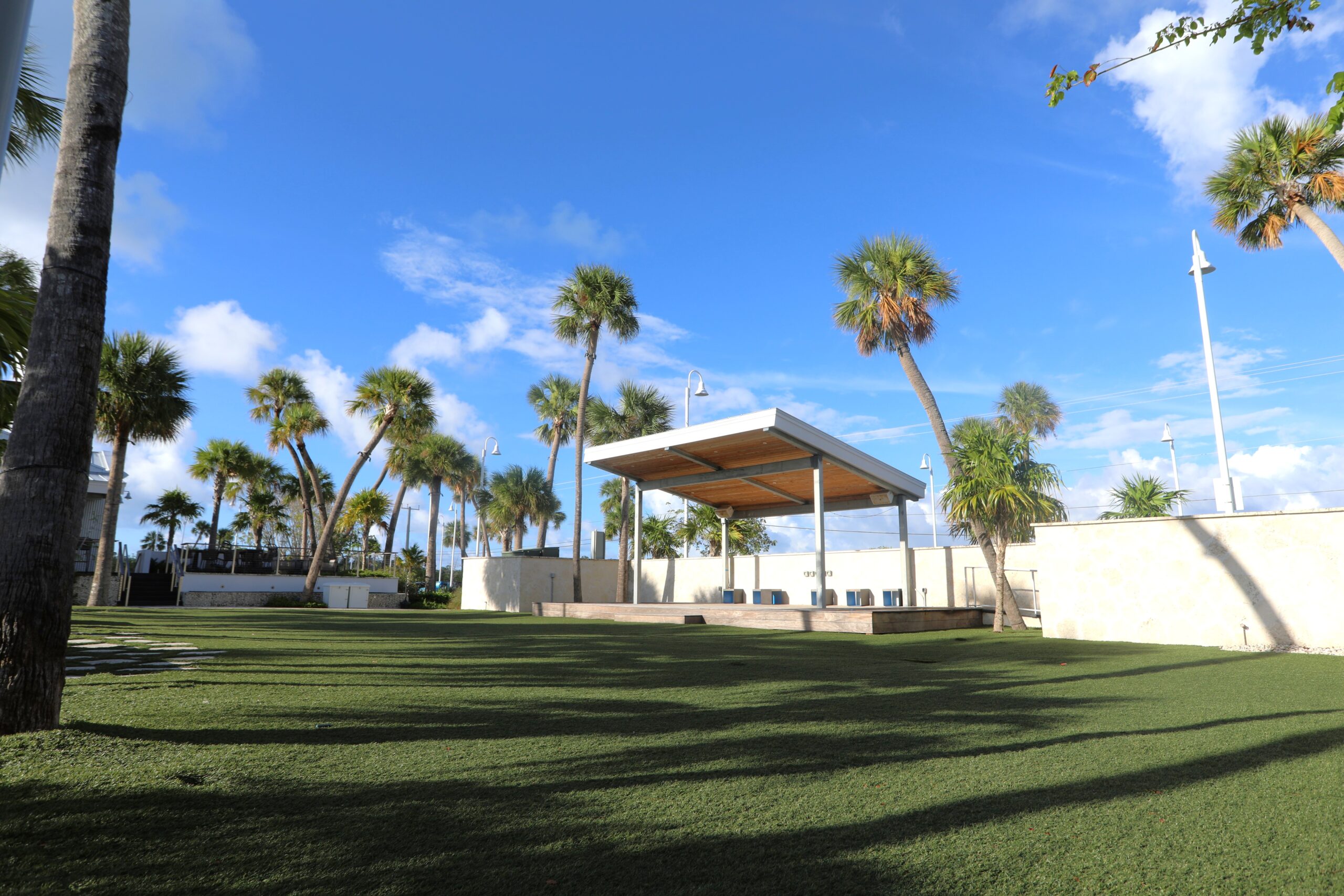 Outdoor event lawn with stage and palm trees.