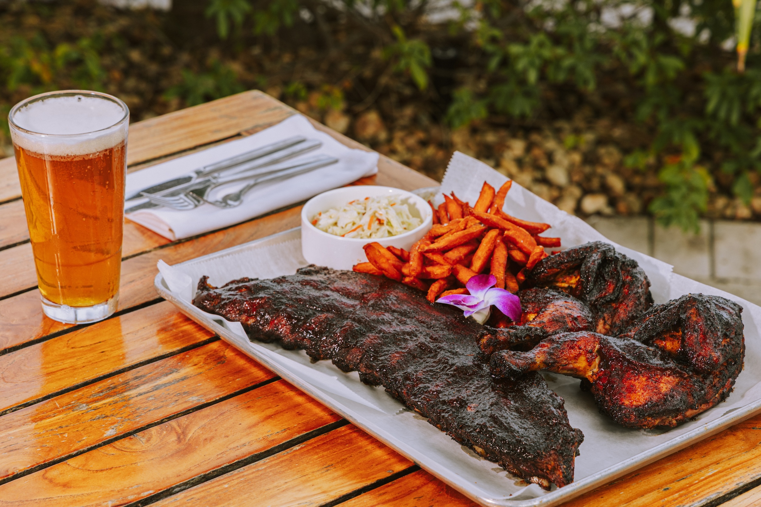 bbq food served outdoors with sweet potato fries and beer