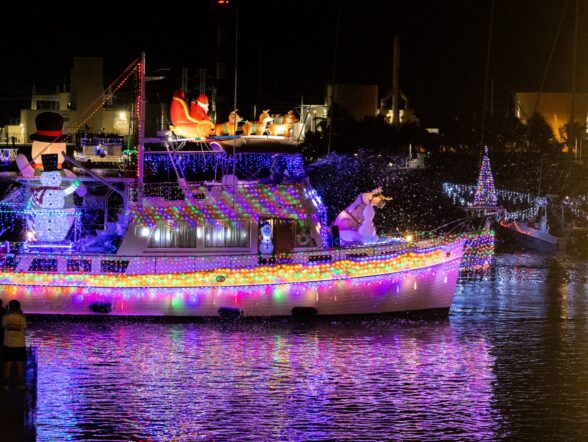 Holiday lighted boat decorated with colorful lights, Santa and a snowman, glowing on the water at night in Key West