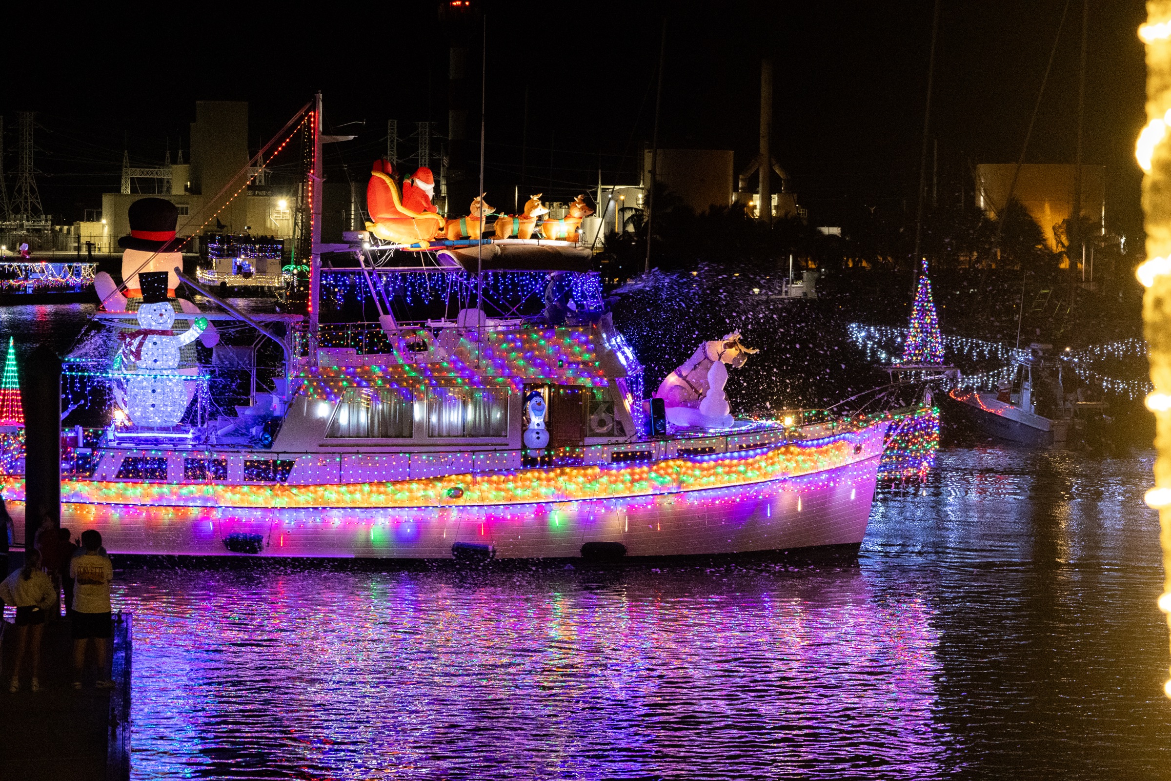 Holiday lighted boat decorated with colorful lights, Santa and a snowman, glowing on the water at night in Key West